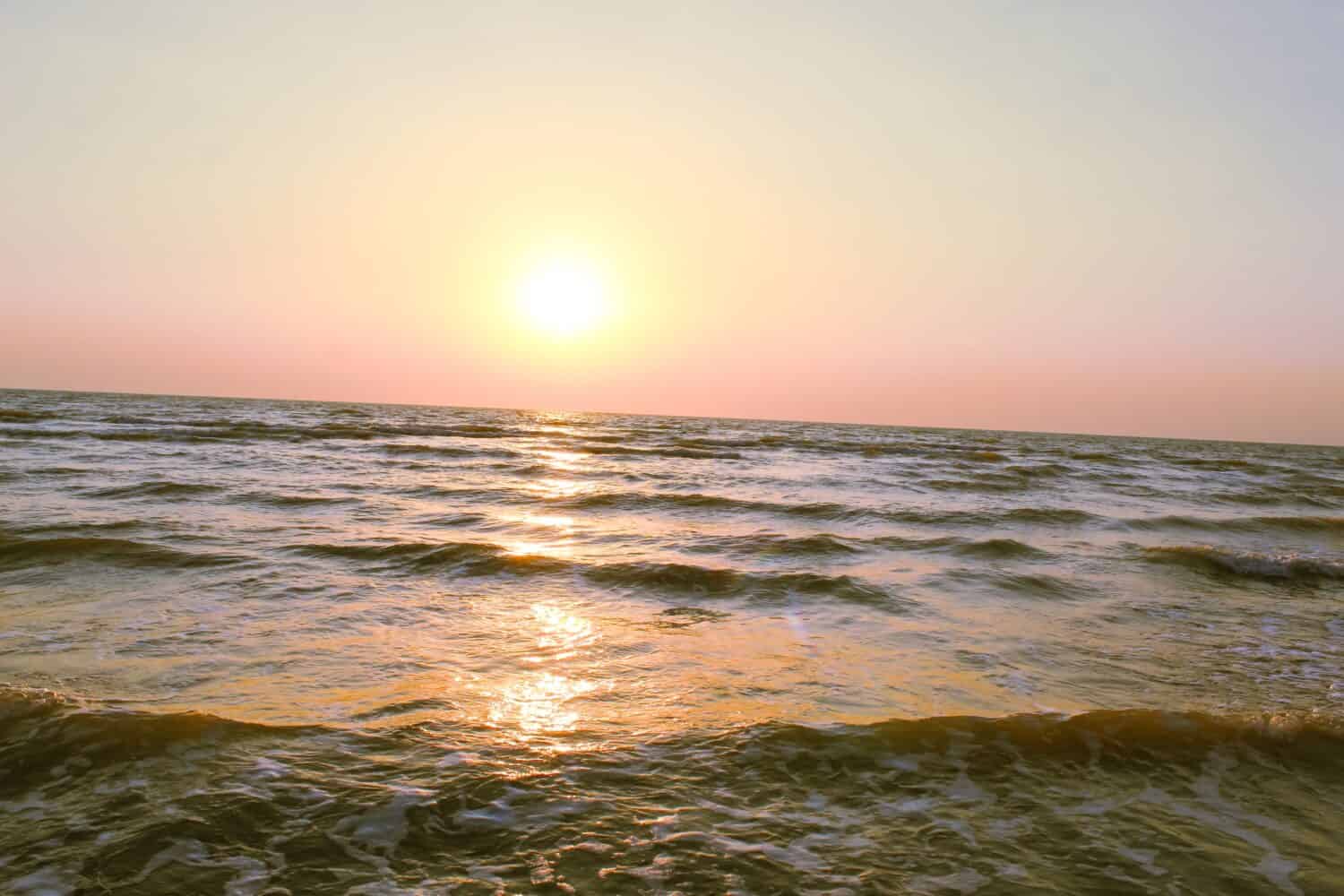 Beautiful summer sunset and the reflection of sunlight on the roaring waves of the ocean waters , roaring sea