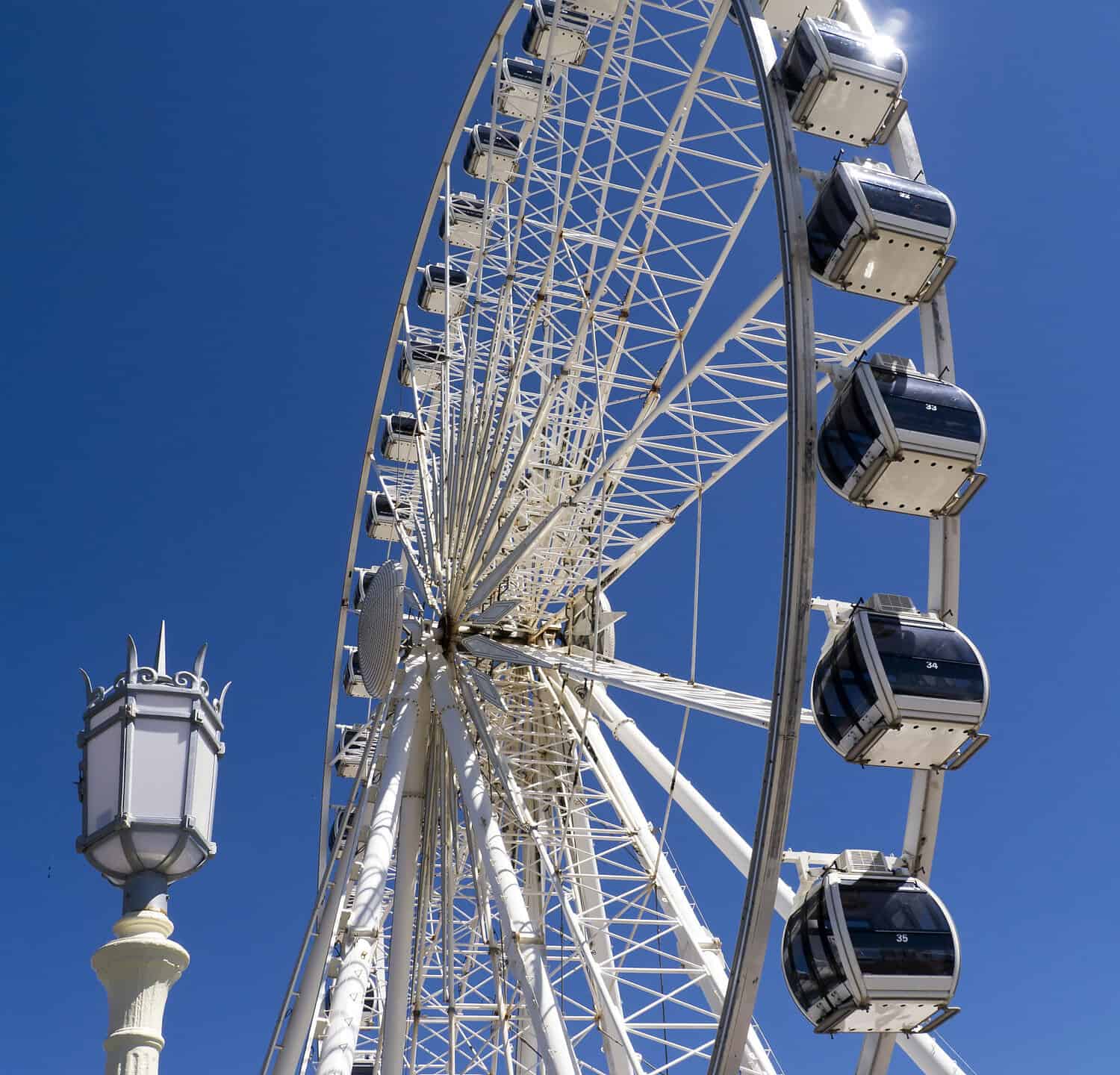 Brighton Eye Ferris Wheel; silhouetted against deep blue sky with street lamp in foreground
