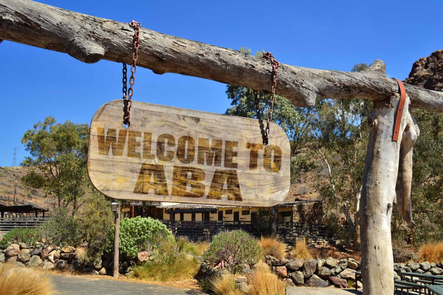 old vintage wood signboard with text " welcome to Aba" hanging on a branch