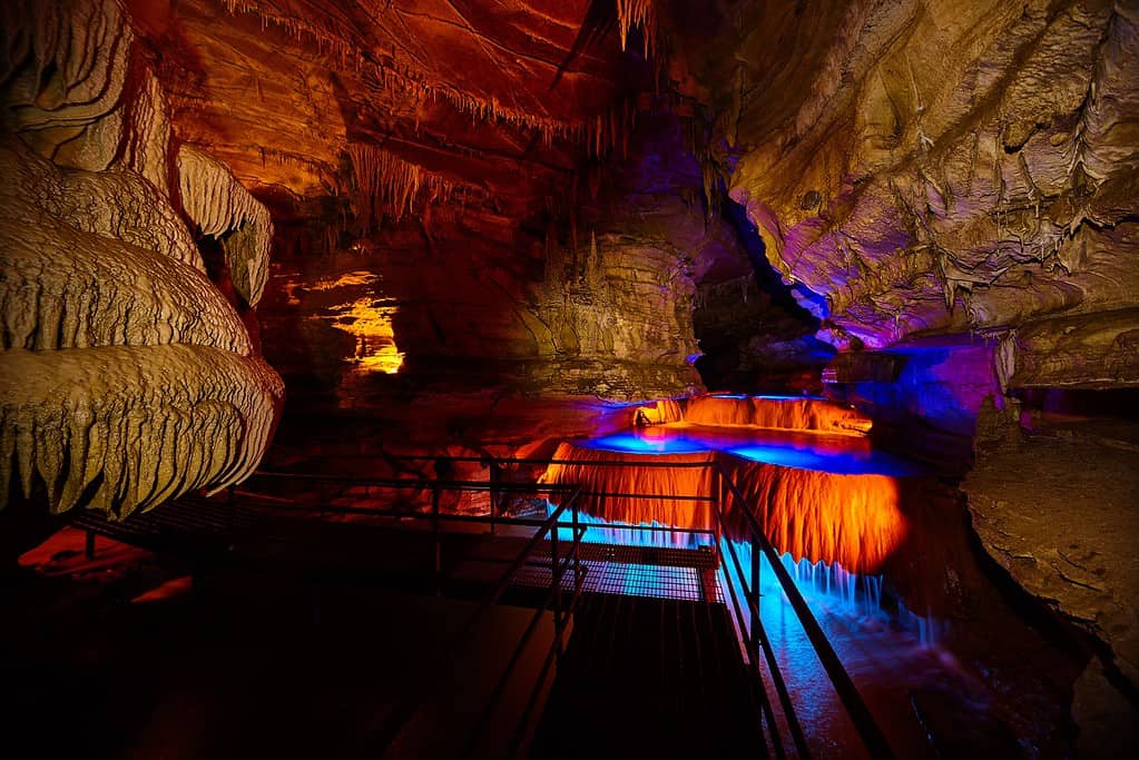 Tour path through Indiana underground cave with waterfall lite by blue and orange lights
