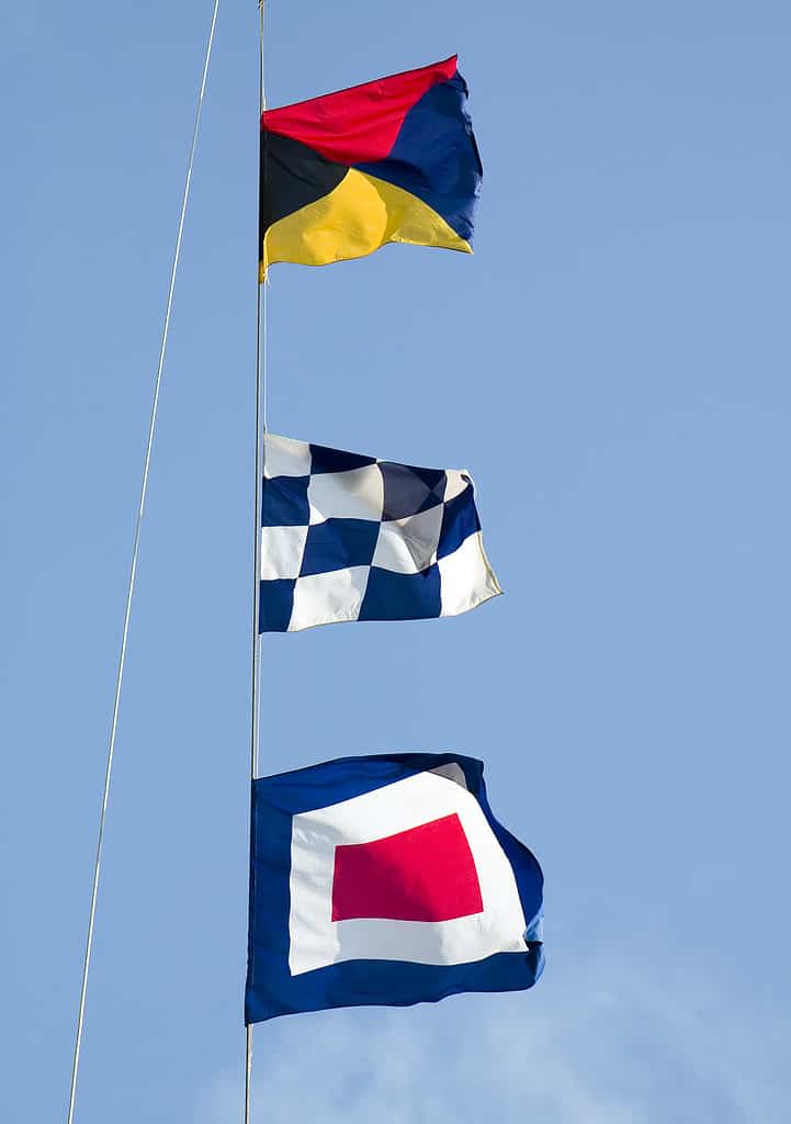 Three international maritime signal flags against a blue sky