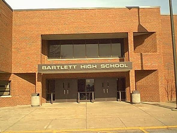Photogrph of the front of Bartlett High School in Bartlett, Tennessee. The school is a salmon brick with the words "Bartlett High School" across the front doors.