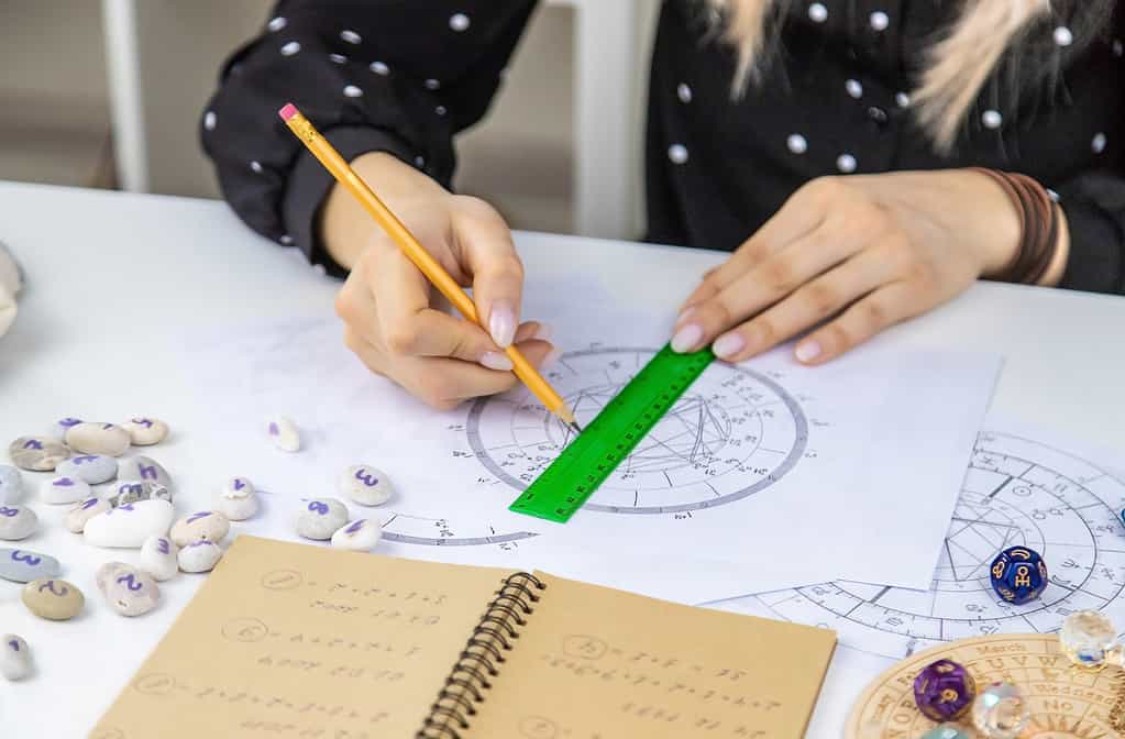 Woman astrologer draws a natal chart. Selective focus.