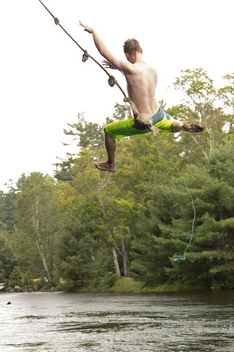 Teenager flying high on rope swing over water