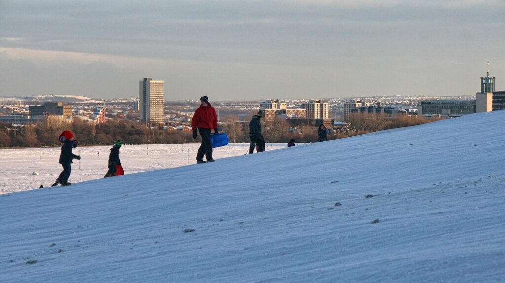 The Town moor in winter. People are sledding on the snow covered hill in Newcastle, England