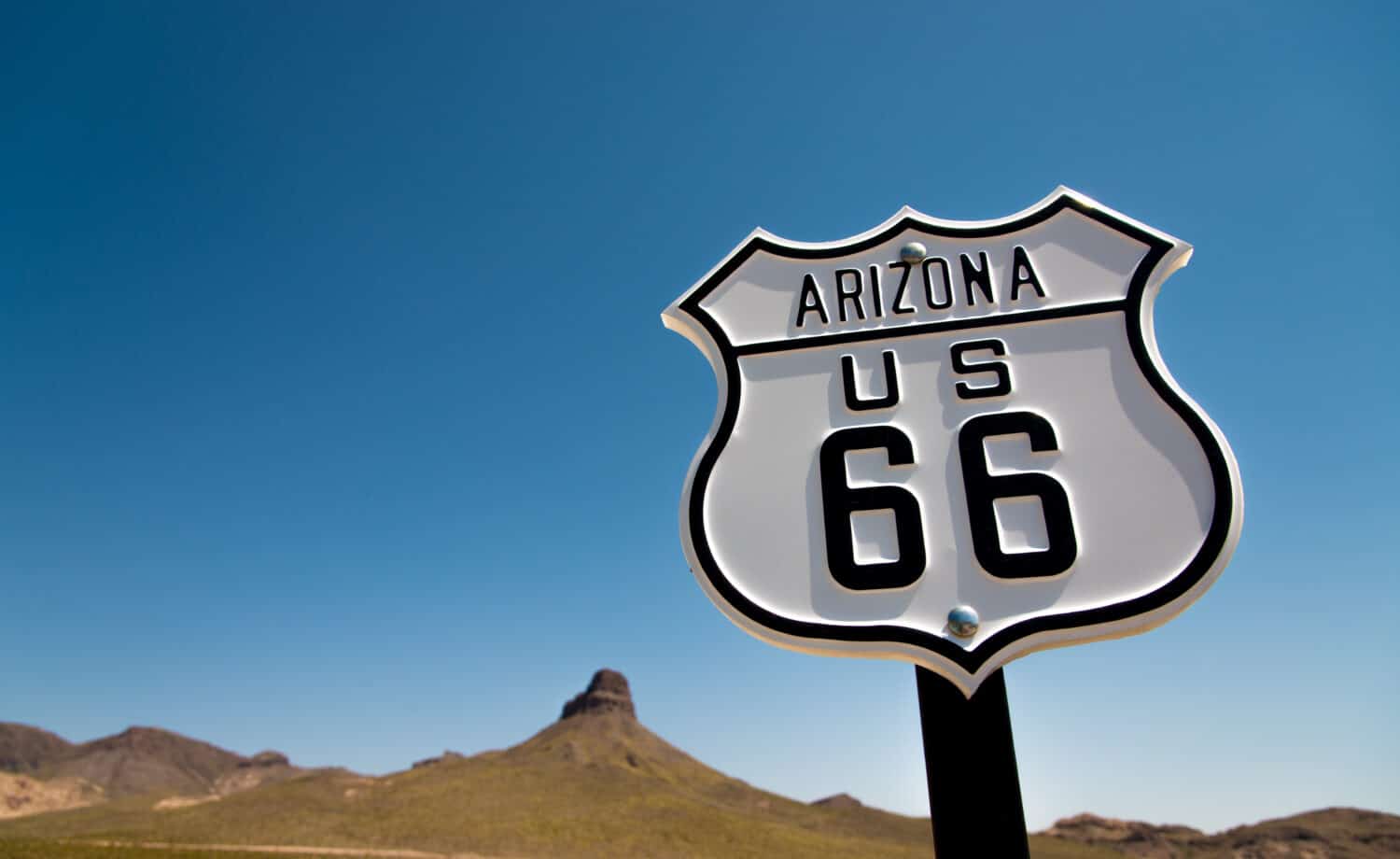 A scenic view of a historic Route 66 sign with a sky blue background