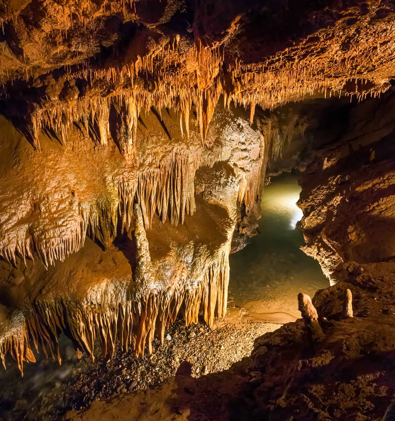 A stream flows beneath delicate rock formations in a subterranean cavern.