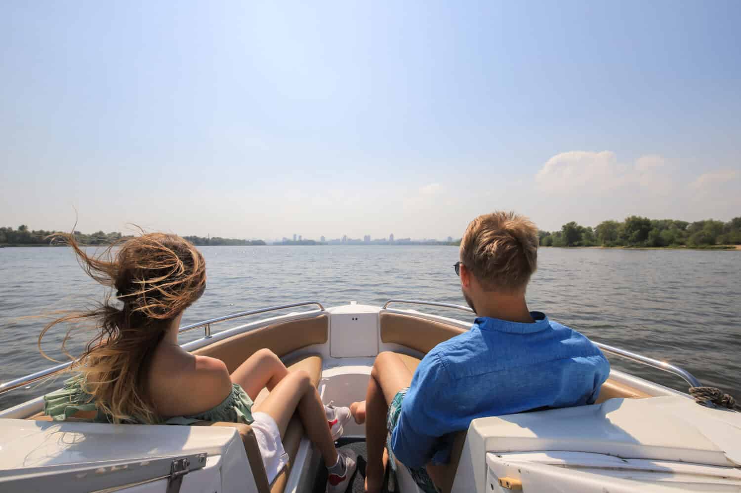 Young couple boating on a motor boat. Boy with girl on the boat enjoy cruise trip.