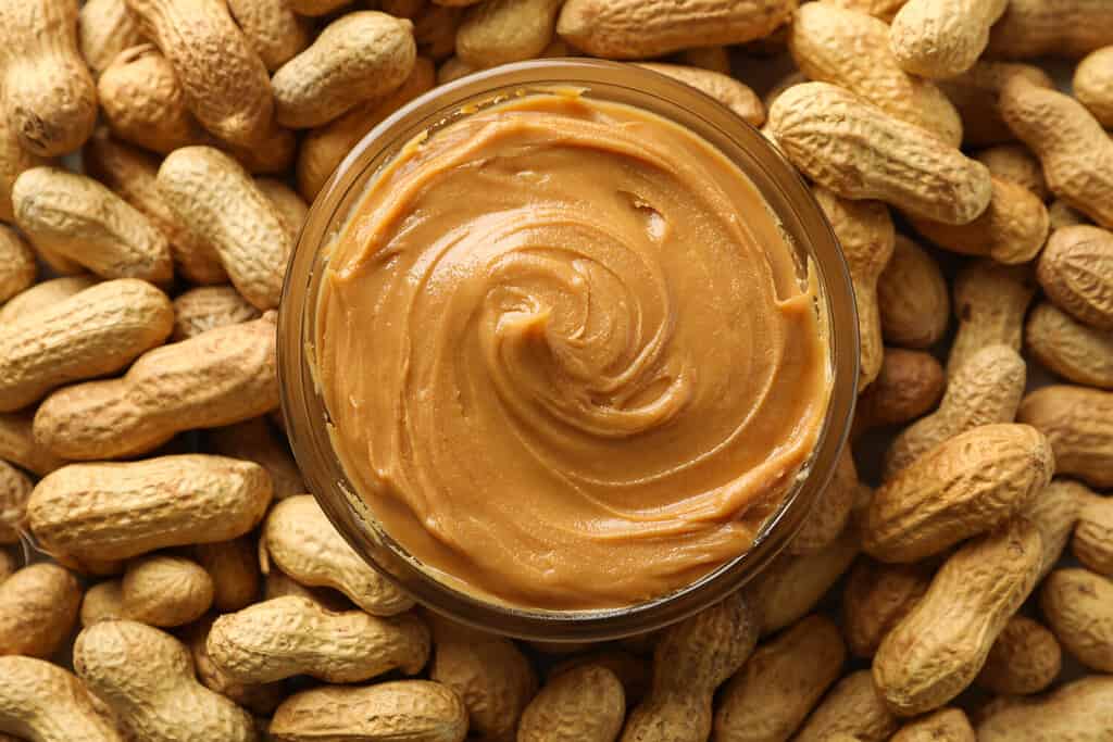 Jar with peanut butter on peanut background, close up