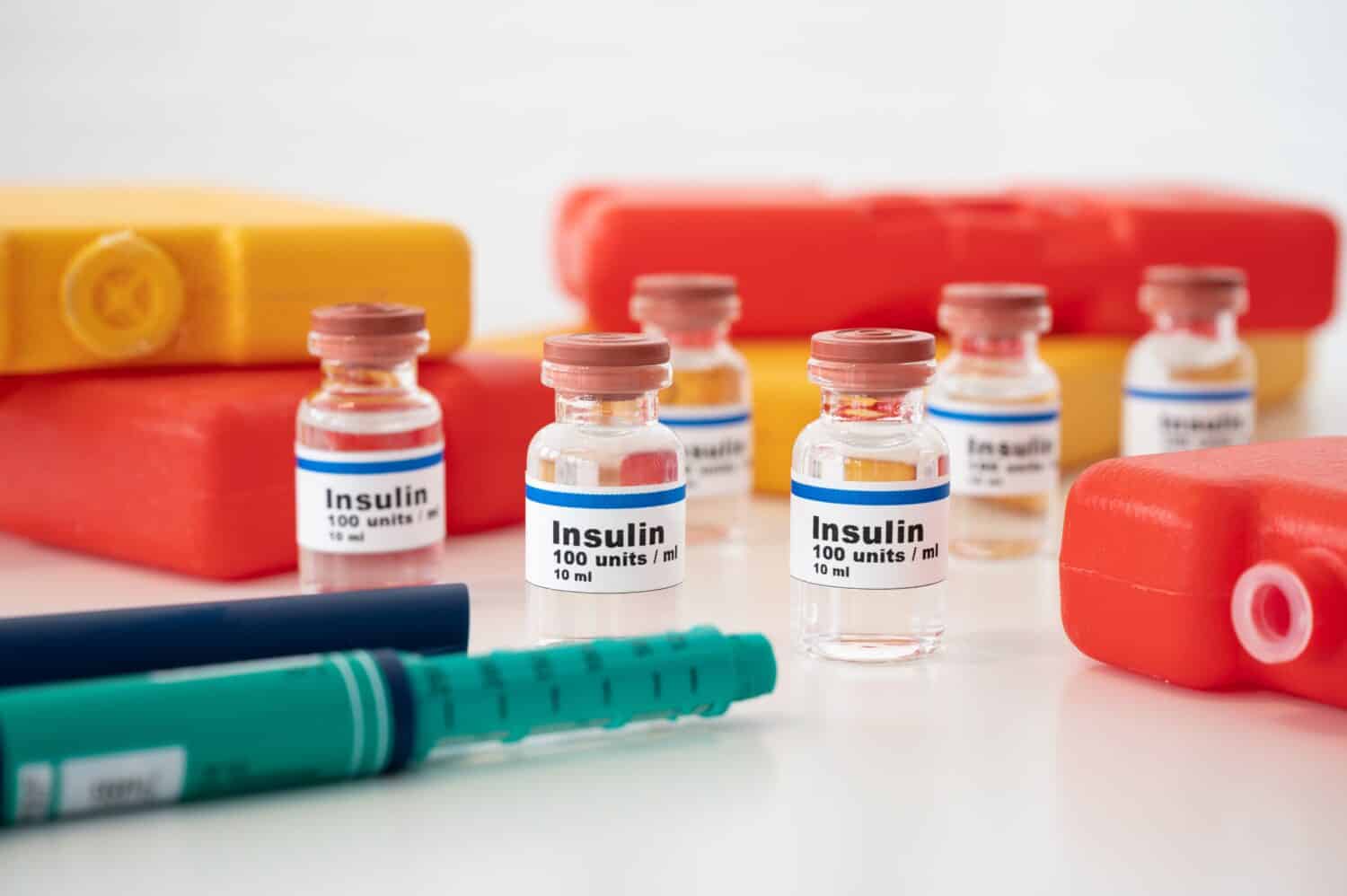 Insulin ampoules and insulin syringe with cold packs against a white background: properly cooling and storing insulin. 