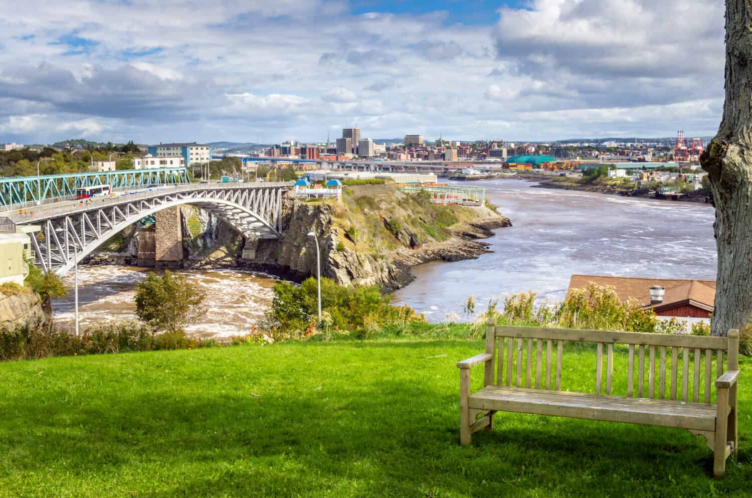 Saint John, New Brunswick, from the Reversing Falls Park with an Empty Wooden Bench in Foreground.