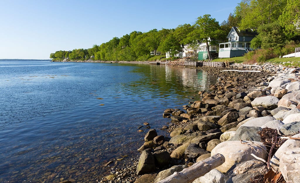 View of a rocky coastline in the foreground with small vacation cottages in the background at Northport, Maine in the early morning light.