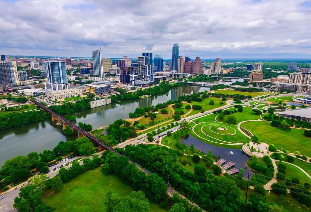 Aerial Over Austin Texas spring time colors with Railroad Tracks crossing Lady bird lake at Zilker Park and Auditorium Shores with Skyline Cityscape and downtown in the background North of the River