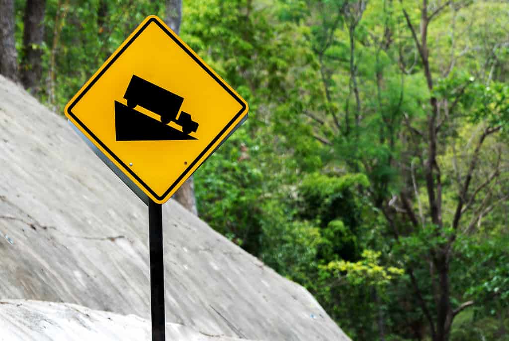 Steep Hill Descent Use Low Gear Traffic Sign on the Road in Mountain