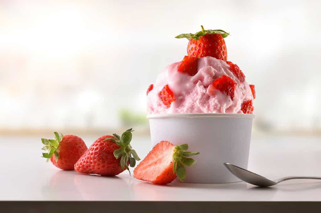 Strawberry ice cream cup on white table homemade with kitchen background. Horizontal composition. 