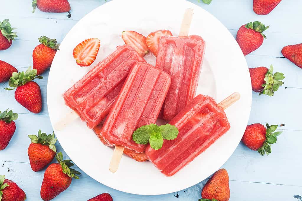 Homemade strawberry popsicles with ice and berries