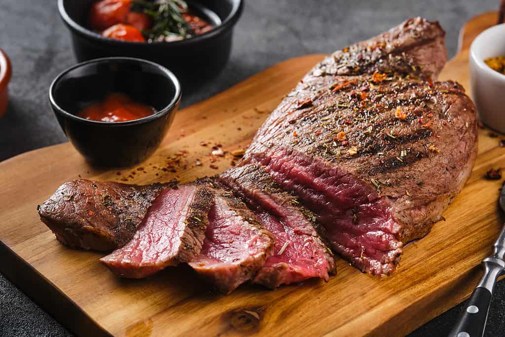 Juicy Beef rump steak from marble beef medium rare with sauce on wooden board, close-up. Selective focus.