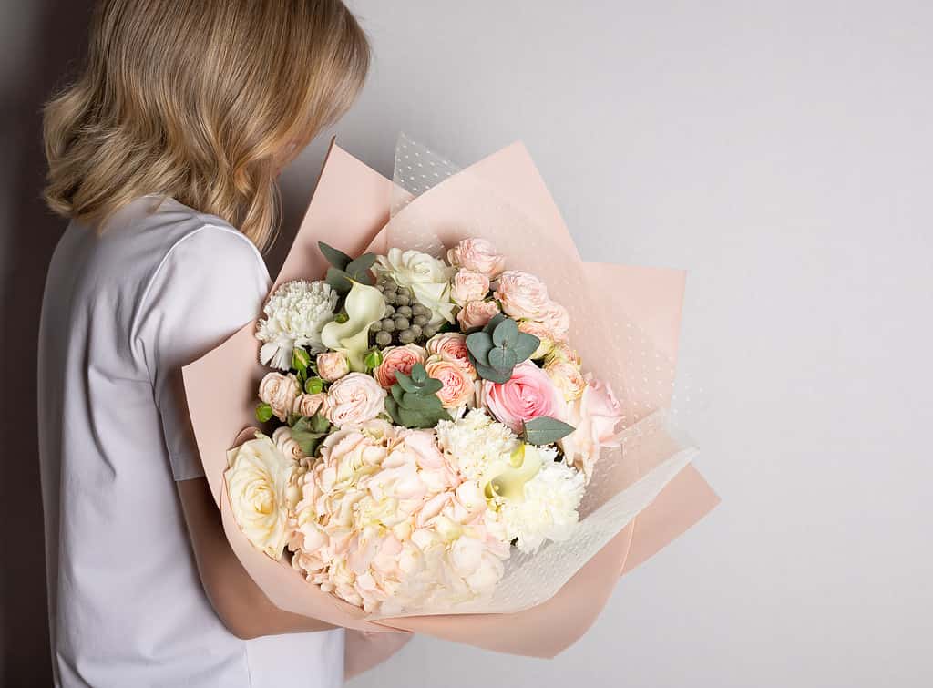 Woman holding large bouquet of hydrangeas, roses