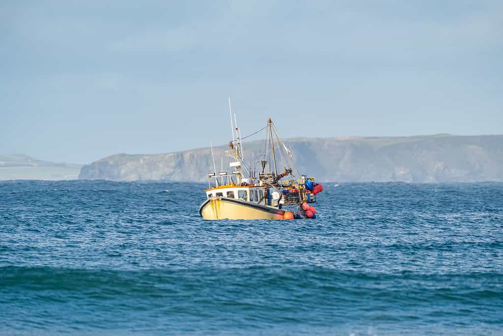 Yellow British fishing boat trawler alone in the English channel islands waters after leaving EU