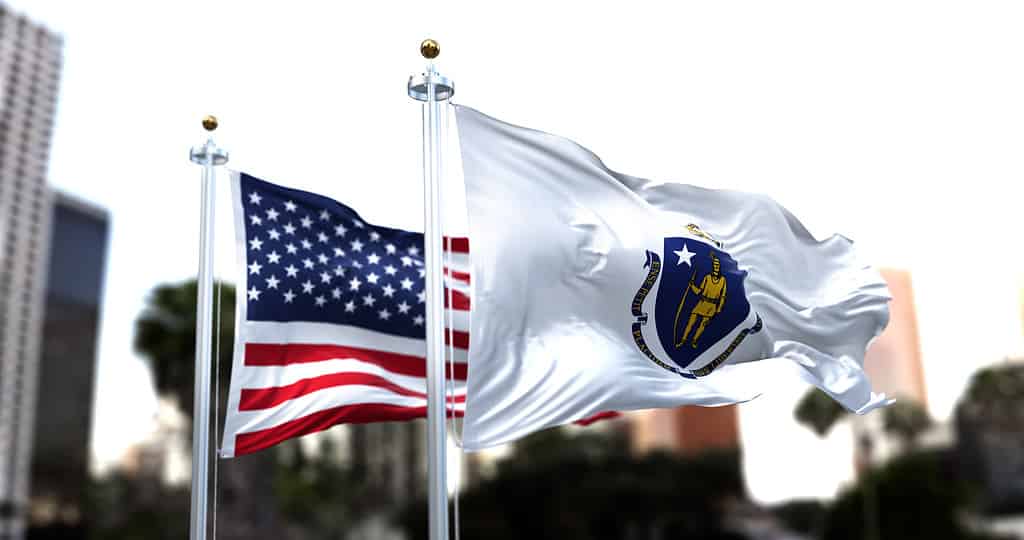 the flag of the US state of Massachusetts waving in the wind with the American flag blurred in the background