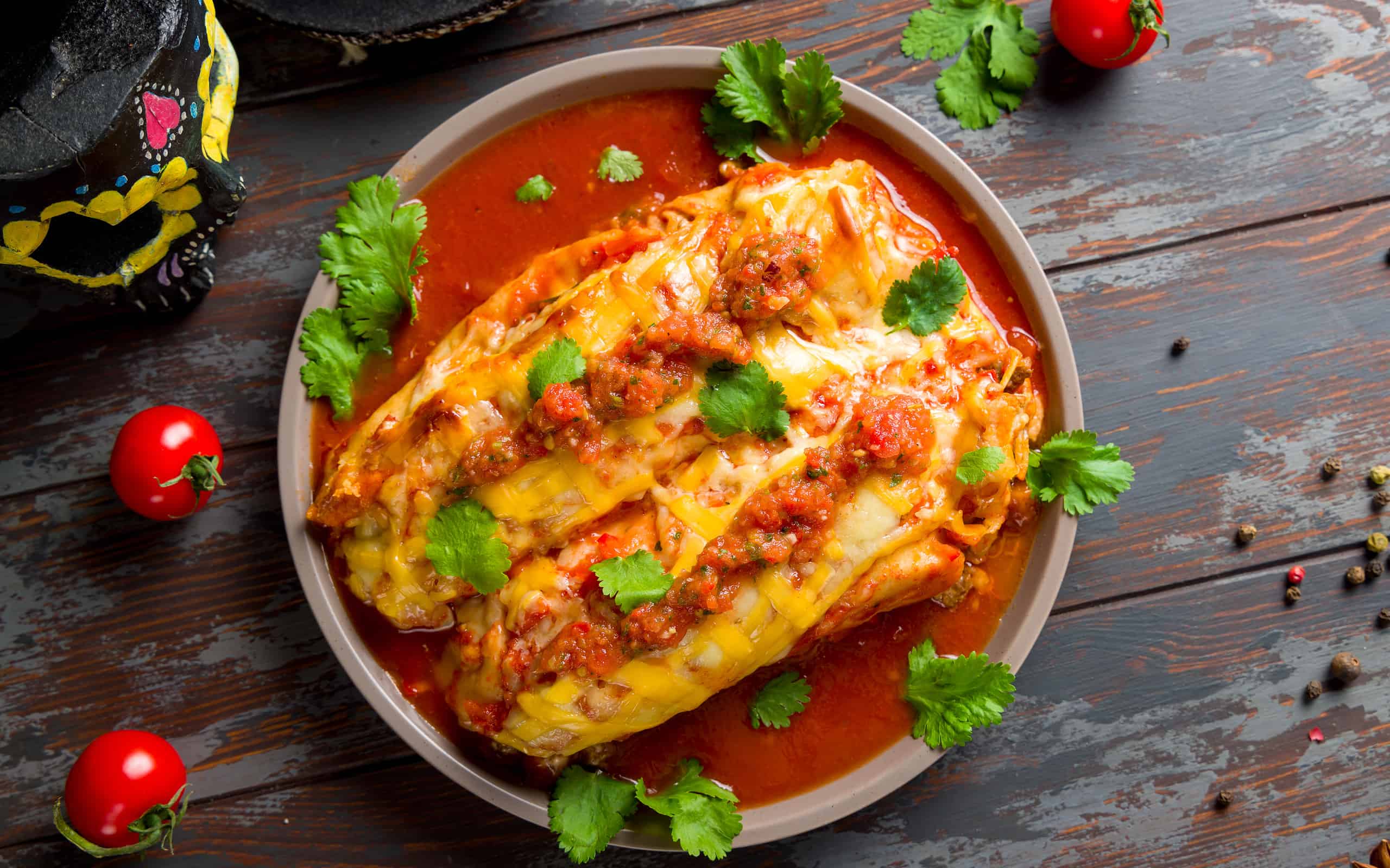 Enchilada with beef with tomato sauce on wooden table, mexican kitchen top view
