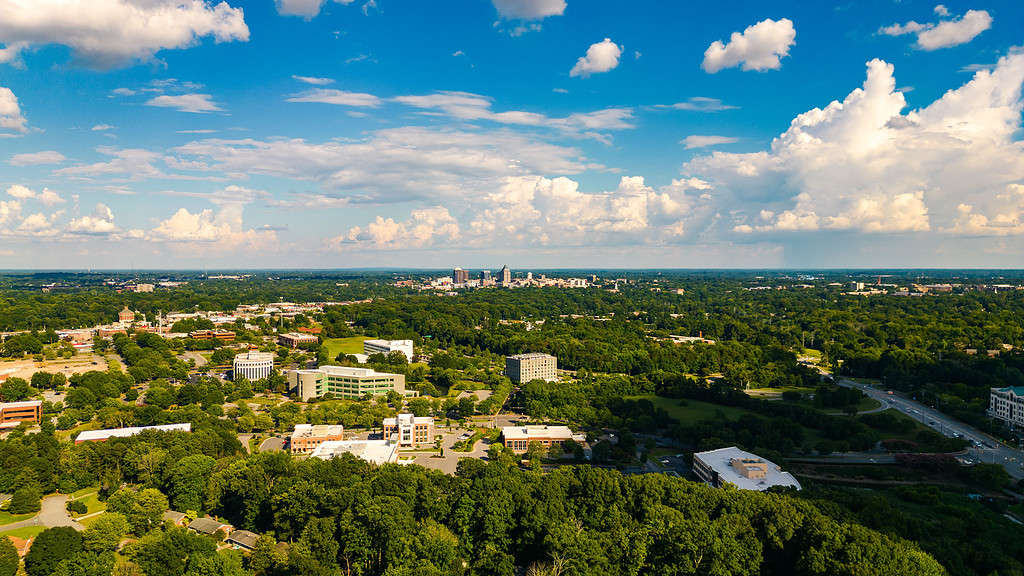Beautiful aerial view of Greensboro with forests and buildings on a sunny day in Piedmont Triad, NC