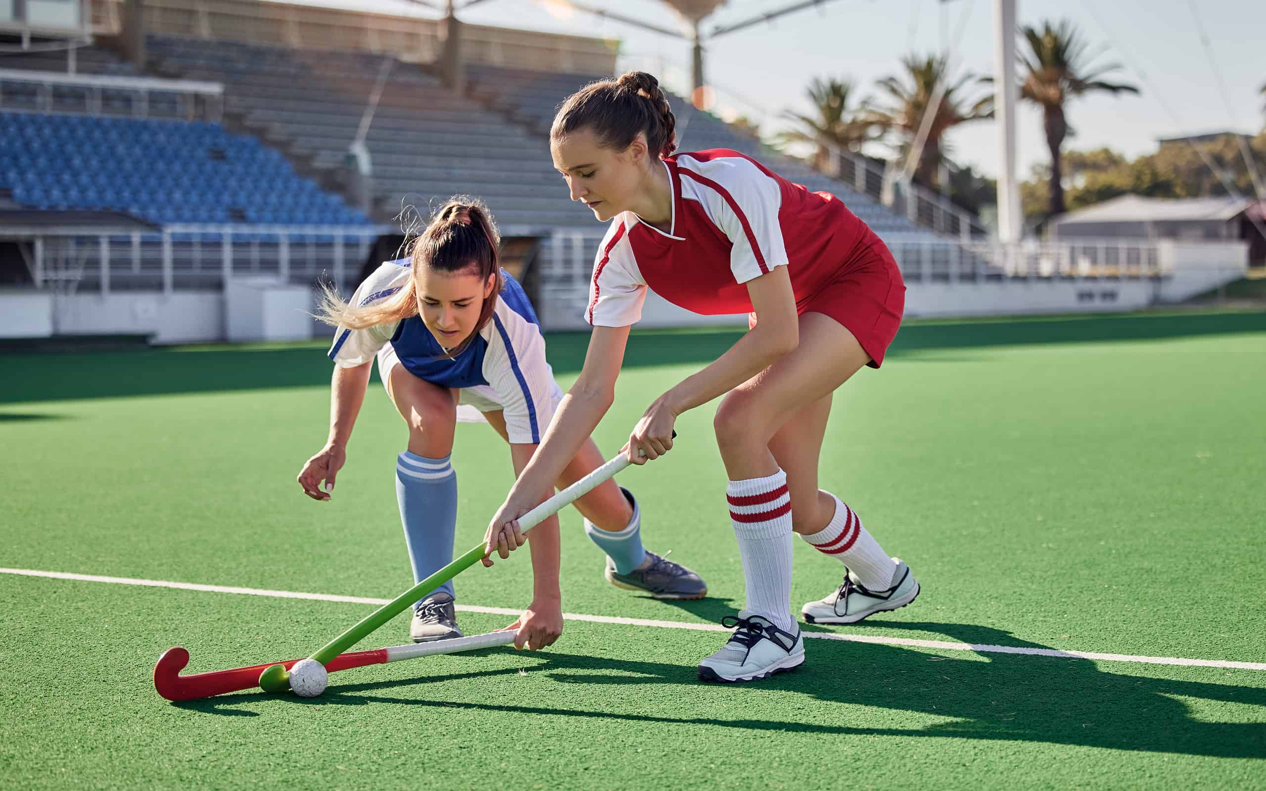 Two competitors battling over the ball during a field hockey game.
