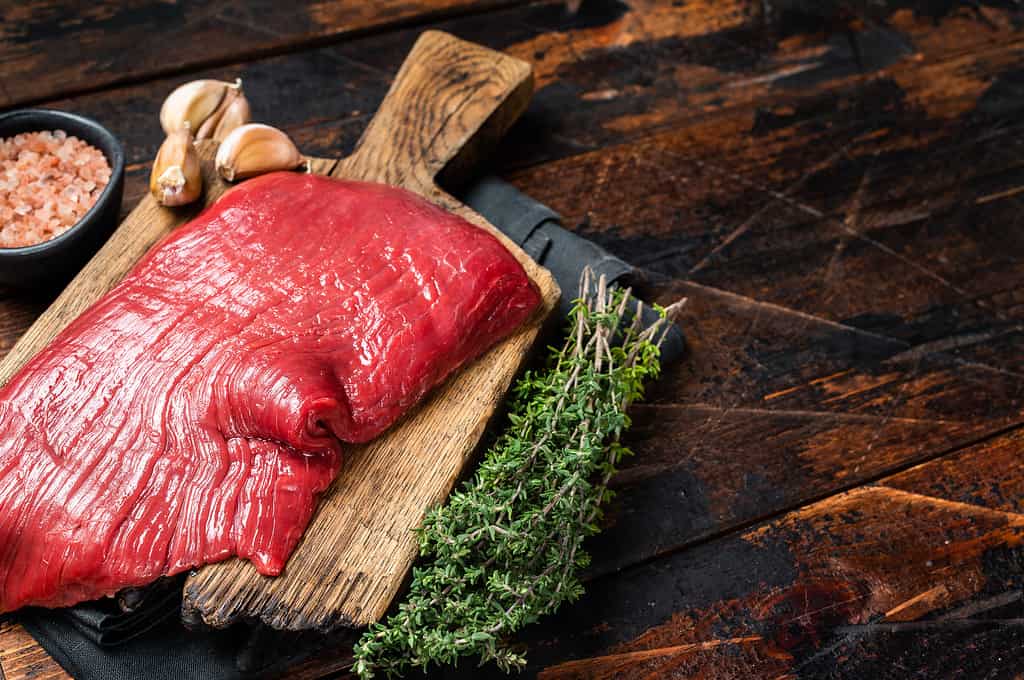Alternative flank beef steak, raw meat. Wooden background. Top view. Copy space
