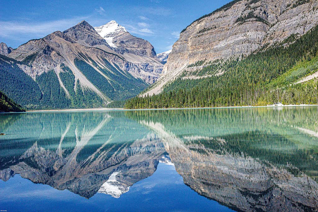 The snow capped peaks of mt Robson are reflected in the still tranquil waters of Kinney Lake