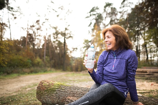 Senior runner in nature with water bottle.