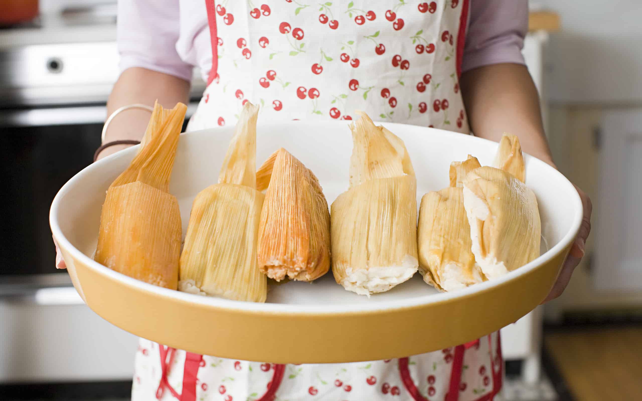 A woman holding a dish of tamales