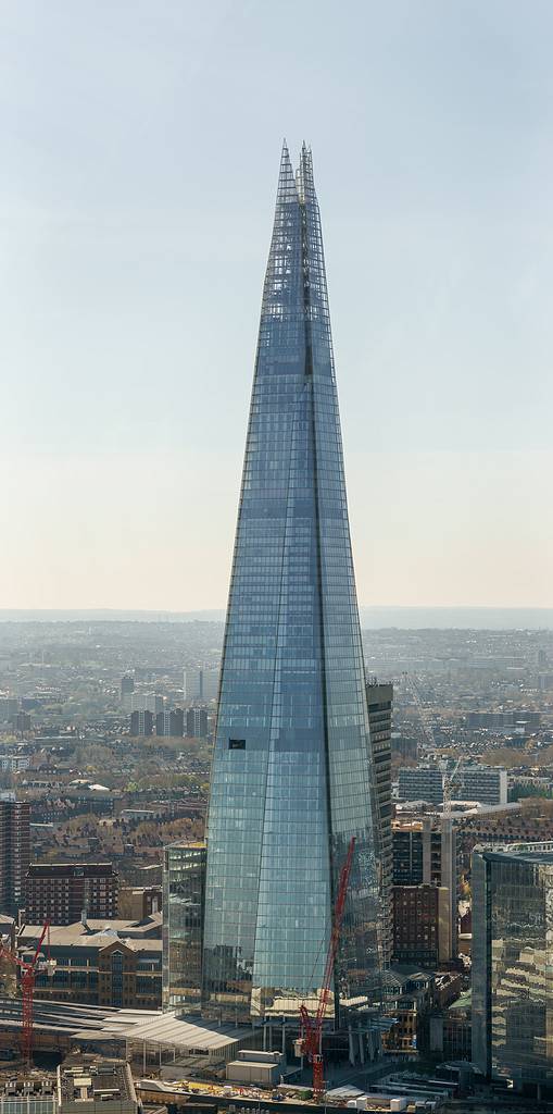 The Shard, taken from the Sky Garden atop the "Walkie-Talkie". A window is open, which allows a crane to lower a box that holds the window cleaners. The people walking at the bottom of this tower are approximately 170 × smaller than the building.