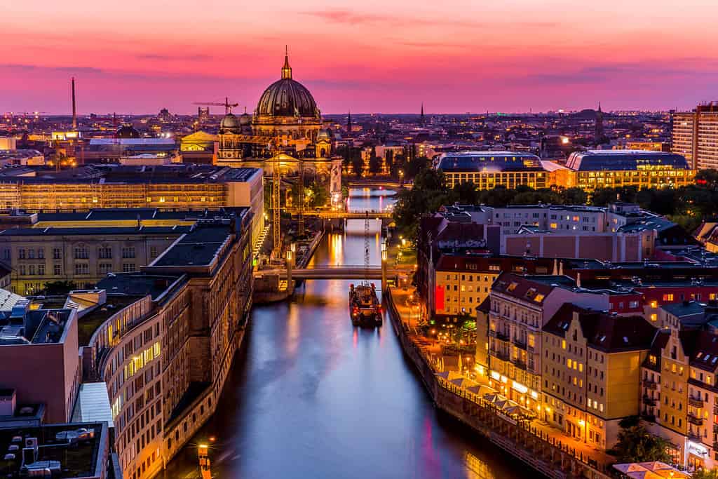 Panoromic aerial view of Berlin skyline with famous TV tower and Spree river in beautiful post sunset twilight during blue hour at dusk with dramatic colorful clouds , central Berlin Mitte, Germany