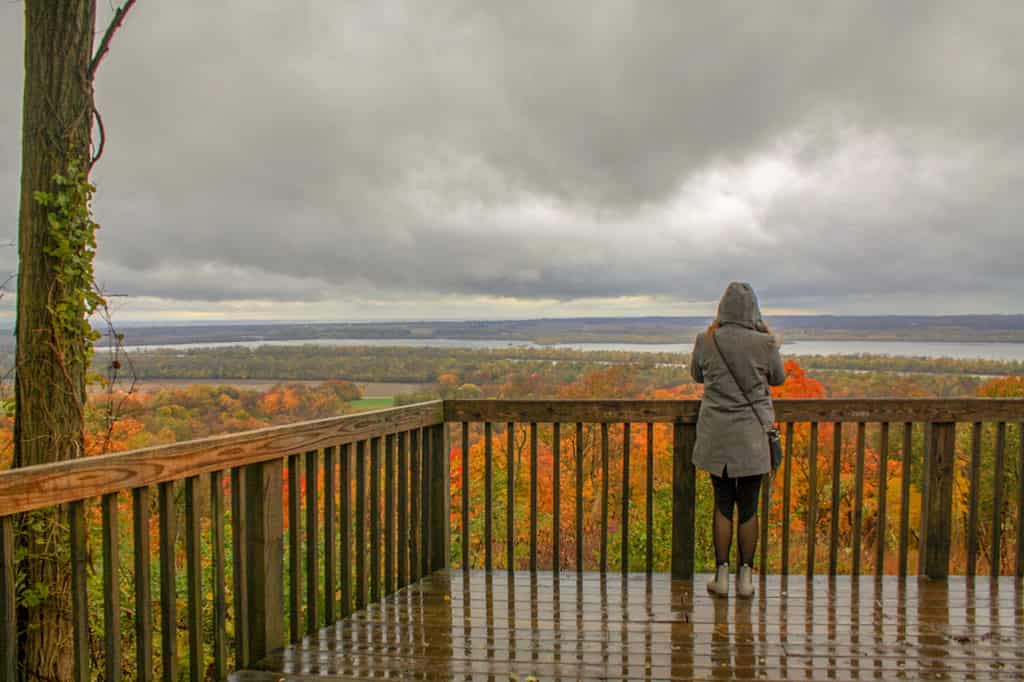 Young Woman overlooking colorful autumn leaves, Mississippi River and grey clouds at Pere Marquette State Park in Grafton Illinois
