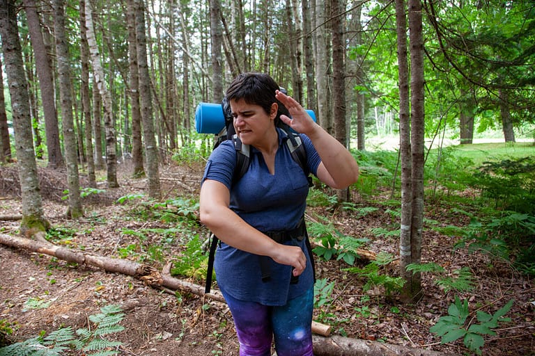 person smacks a tiny insect or mosquito bite while hiking