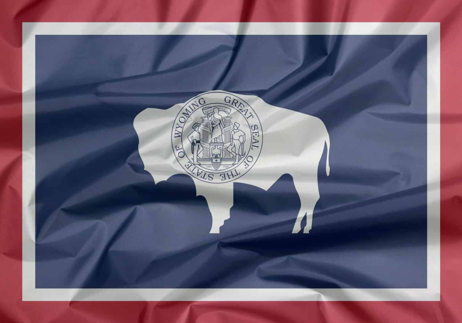 Fabric flag of Wyoming. Crease of Wyoming flag background, the states of America. The seal on American bison on blue with white and red.