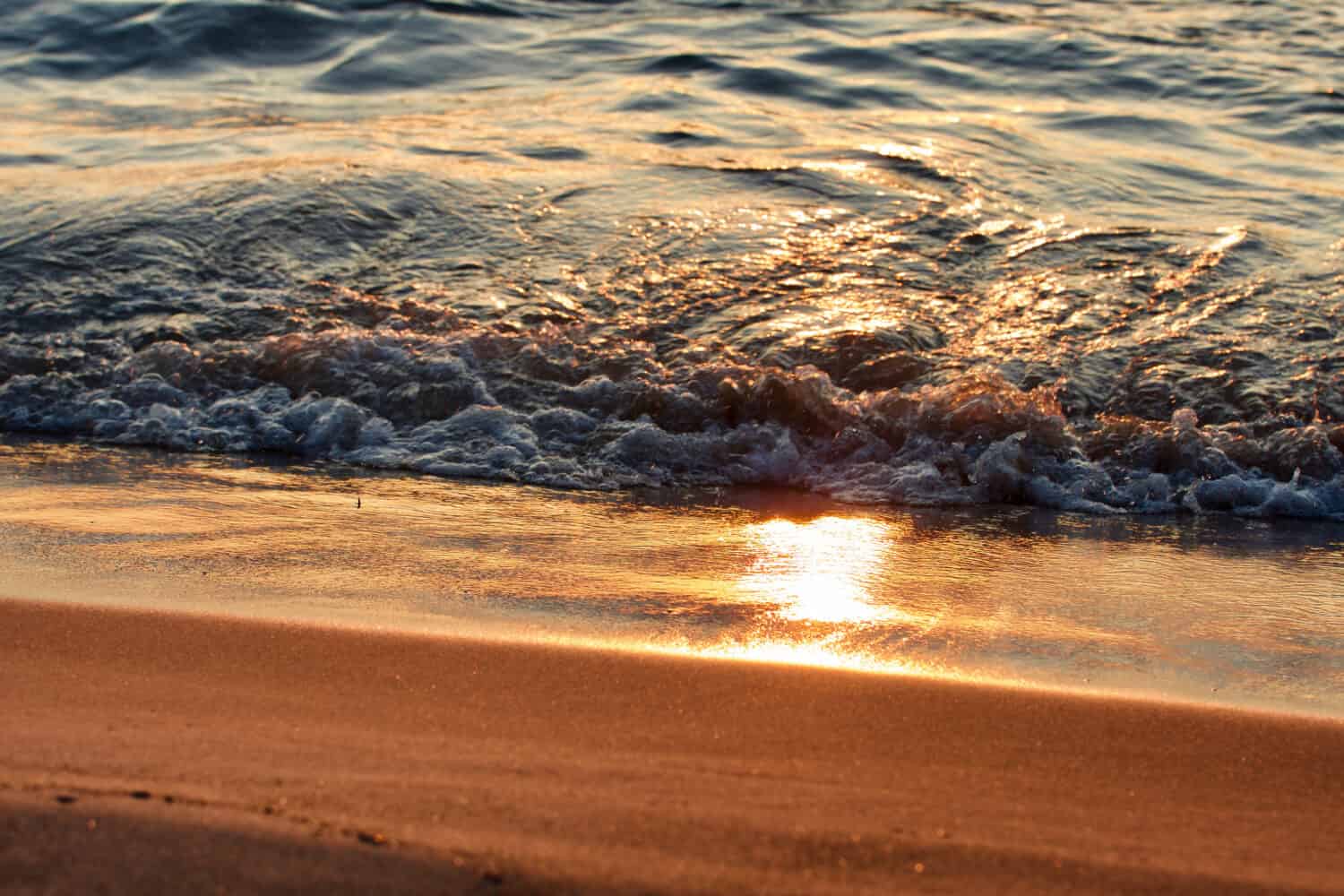 Reflection of the sun in the sand and waves on a beach of Lake Michigan