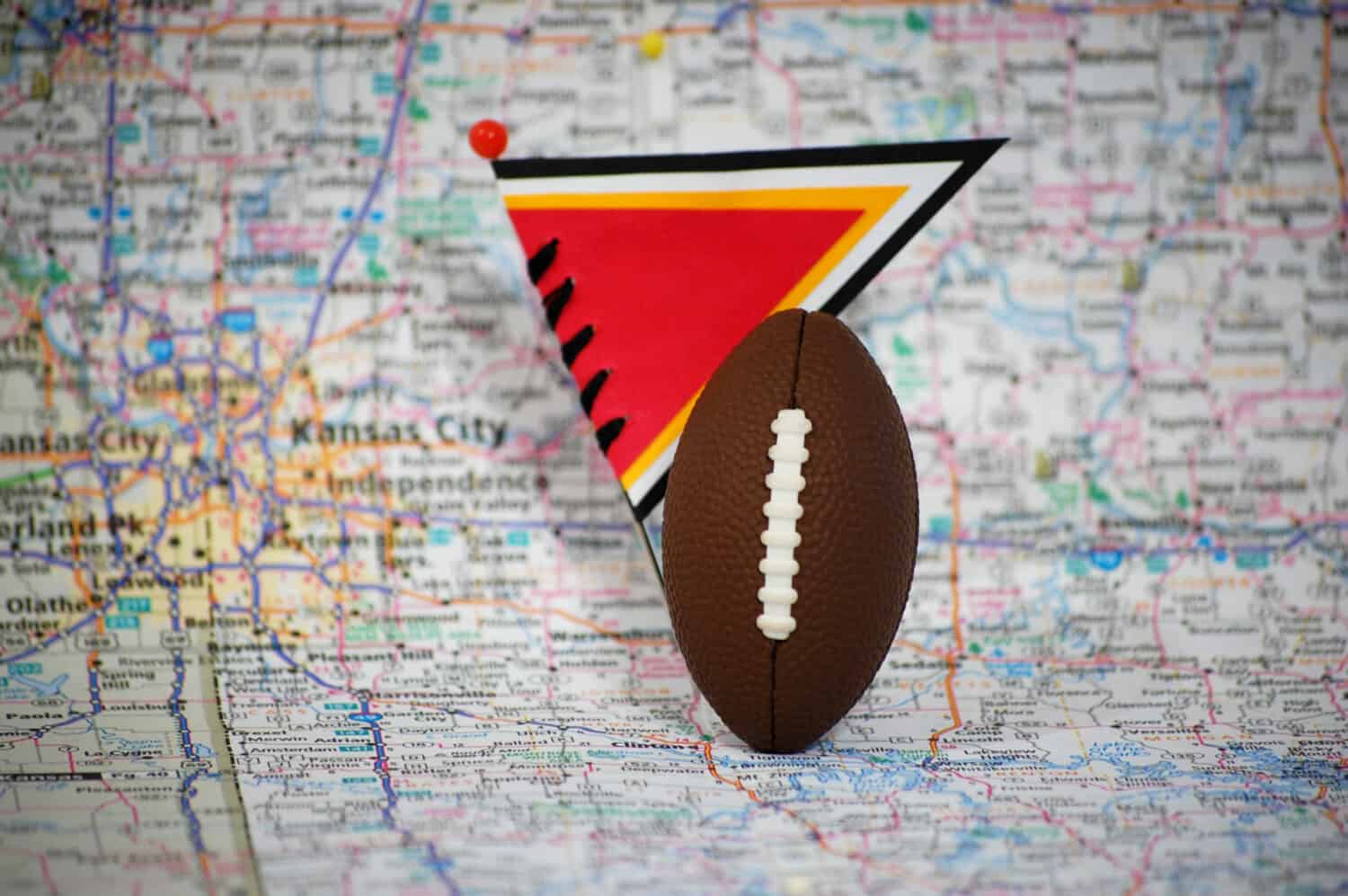 Macro shot of a flag and football on Kansas City, Missouri in a map.