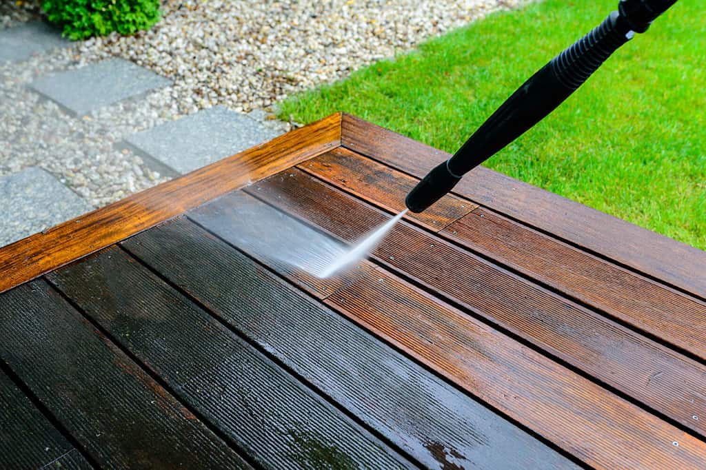 cleaning deck with a power washer - high water pressure cleaner on wooden deck surface