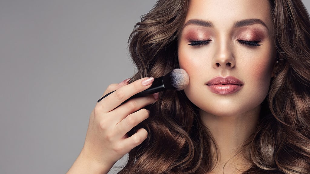 Makeup artist applies applies powder and blush . 