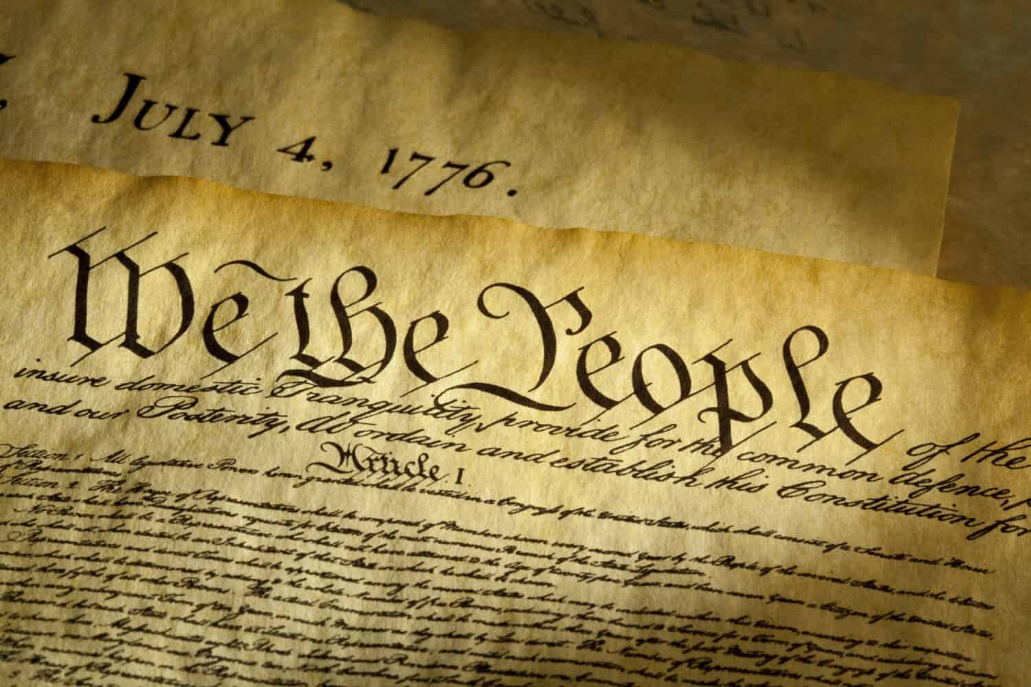 We the People are the opening words of the preamble to the Constitution of the USA. The document underneath is a copy of the Declaration of Independence with the date, July 4, 1776 showing.  