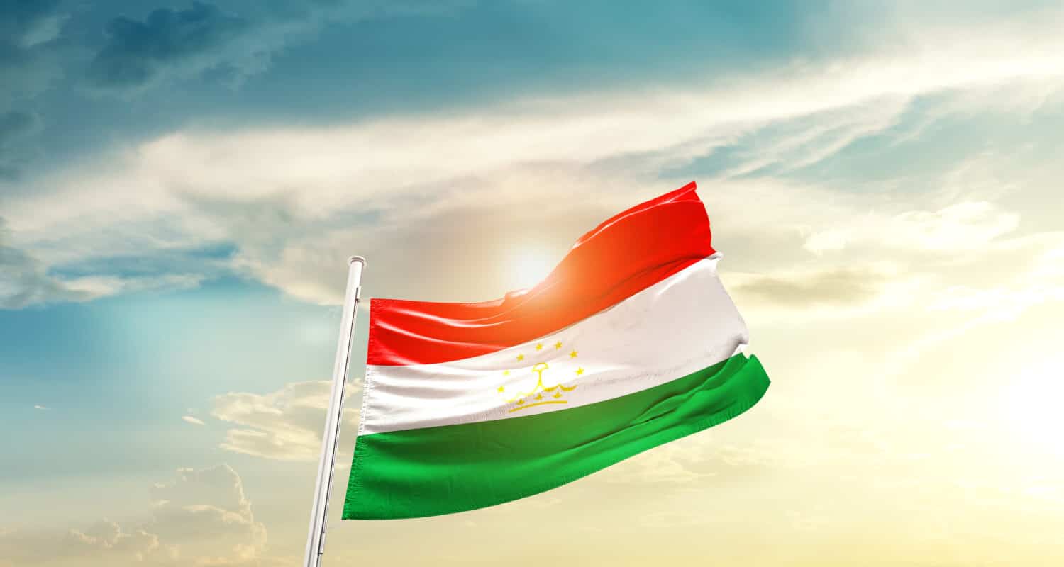 Tajikistan national flag waving in beautiful clouds.