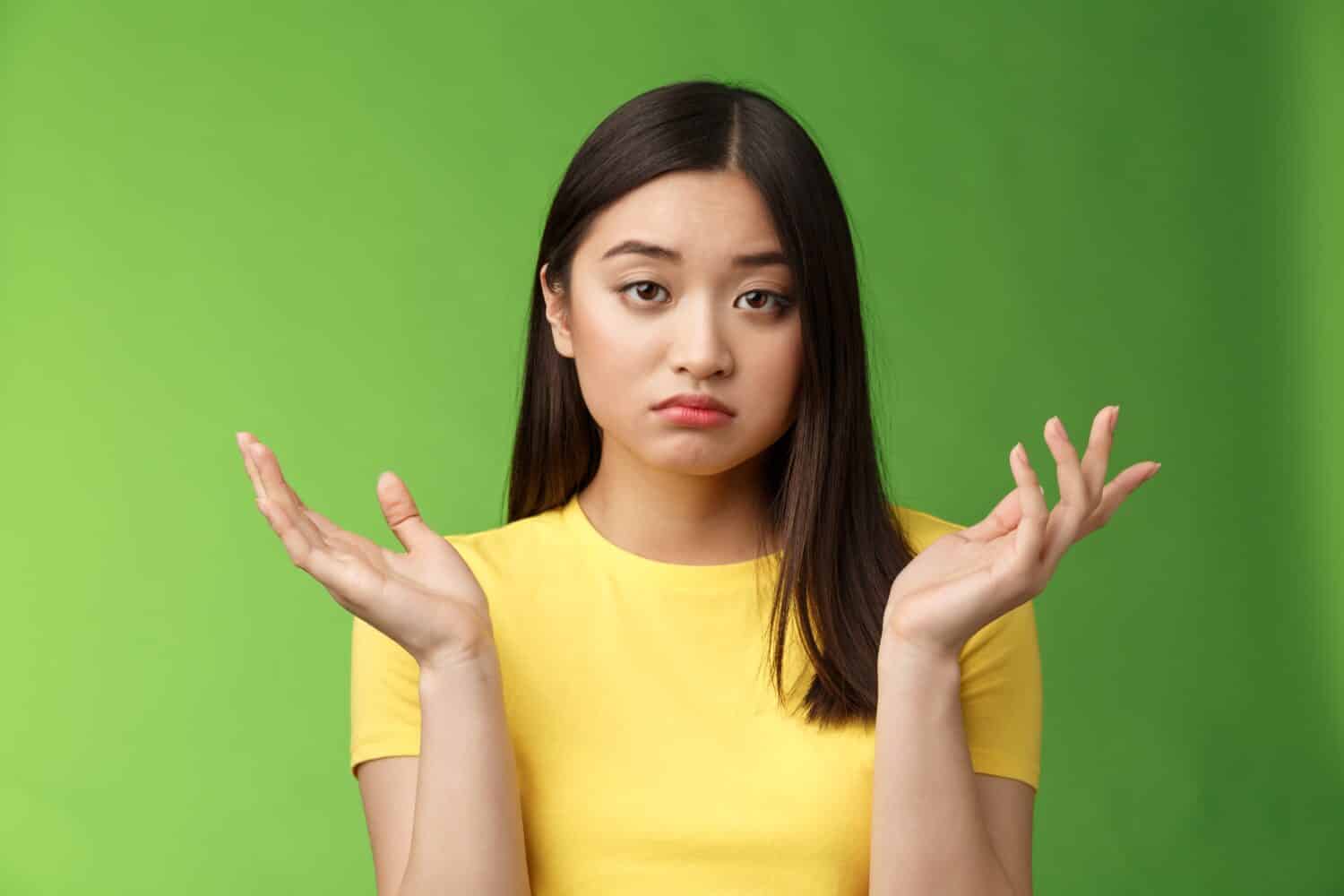 Close-up confused unemotive brunette woman spread hands sideways full dibelief, questioned what happening, look apathy reluctant, stand green background frustrated, no emotions