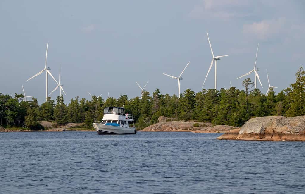 boat anchored near Henvey Inlet on Georgian Bay with wind turbines on the coast