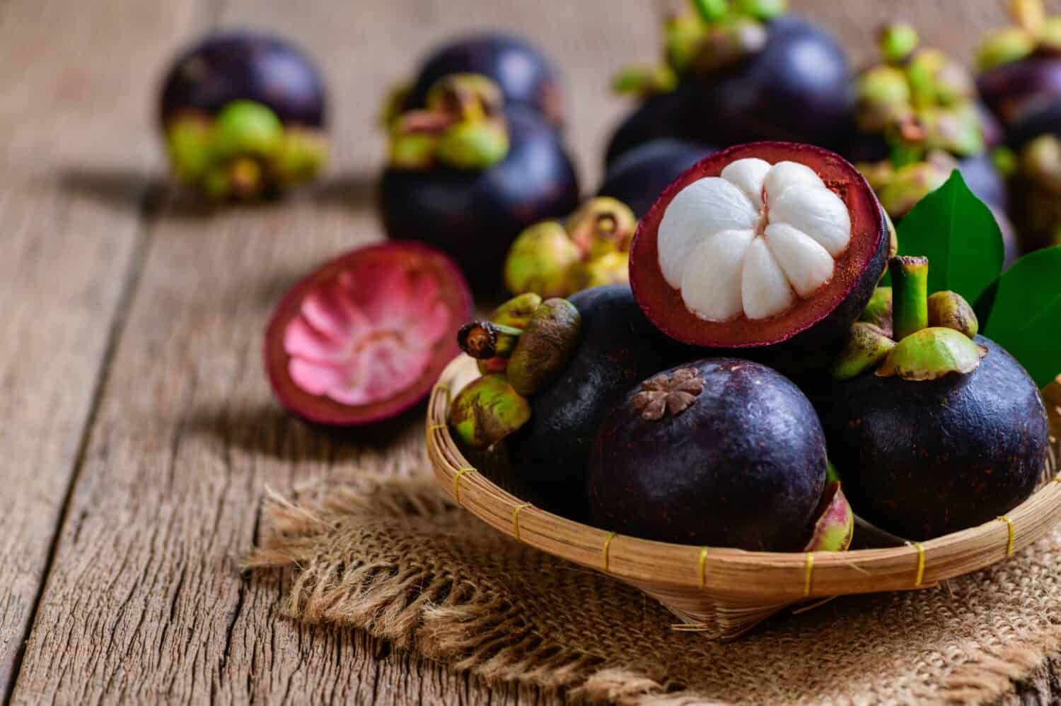 Fresh Mangosteen in bamboo basket and on old wood baclground. Mangosteen has been known as The Queen of Fruits, asia fruits concept