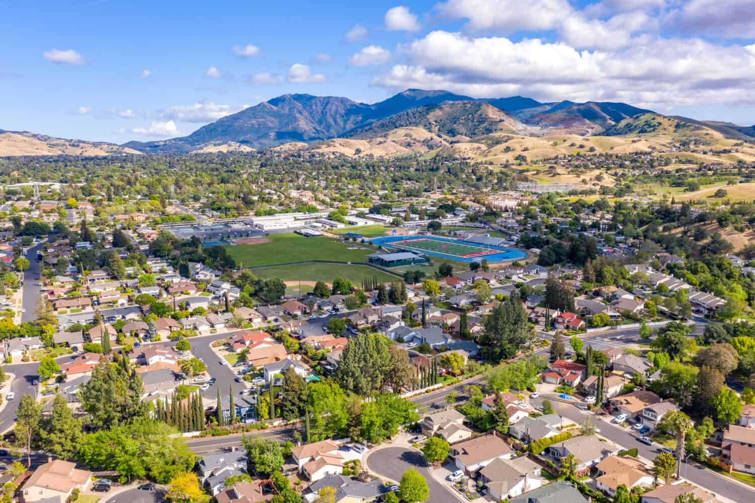 Aerial photo over the city of Concord, California with houses in the foreground and green trees with Mt.Diablo in the background and a blue sky