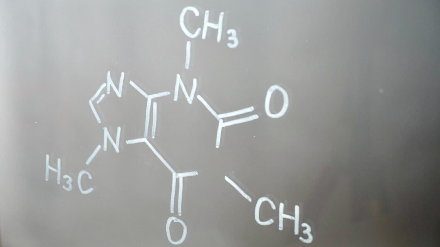 Chemical structure, formula of caffeine on glass in the lab close-up. Showing functional amine and amide groups.