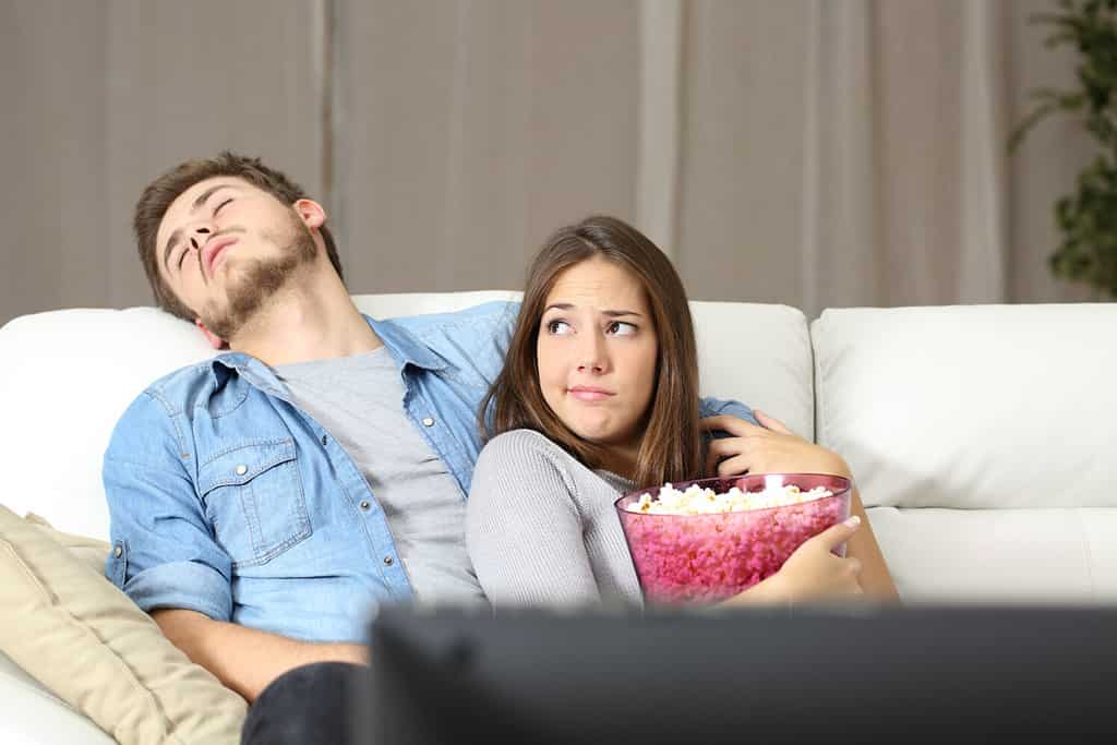 Couple incompatibility problems watching tv sitting on a couch at home