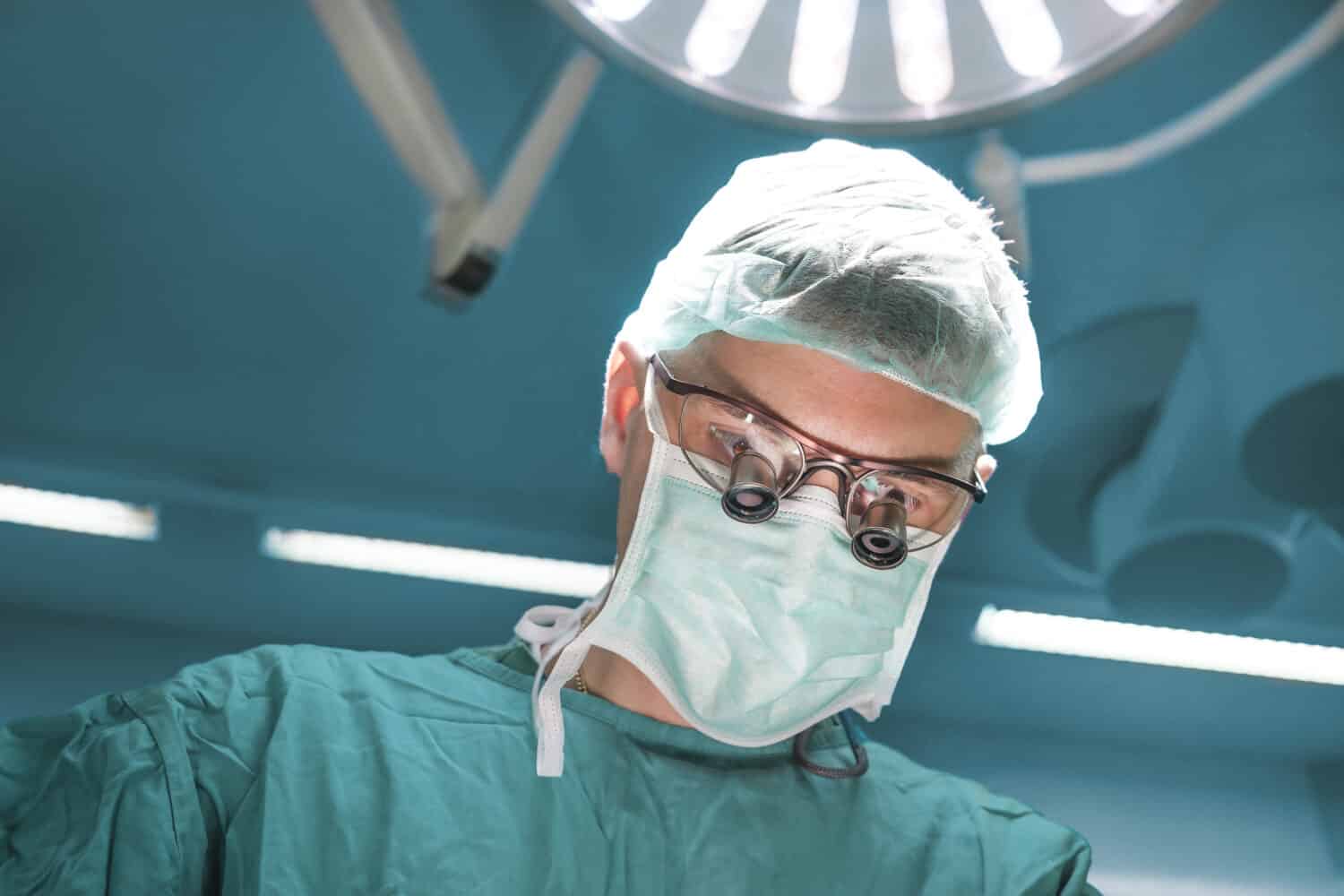 Portrait of a surgeon with magnification glass during the open heart procedure in operating room