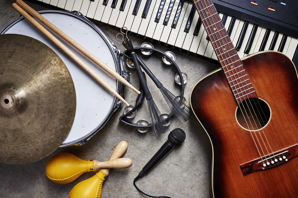 a group of musical instruments including a guitar, drum, keyboard, tambourine.